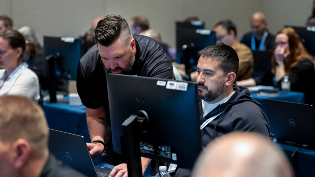 Two people working on a computer at MUS 2026.